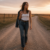 Fashion editorial: woman in denim, white tank, and boots walking a prairie road at golden hour