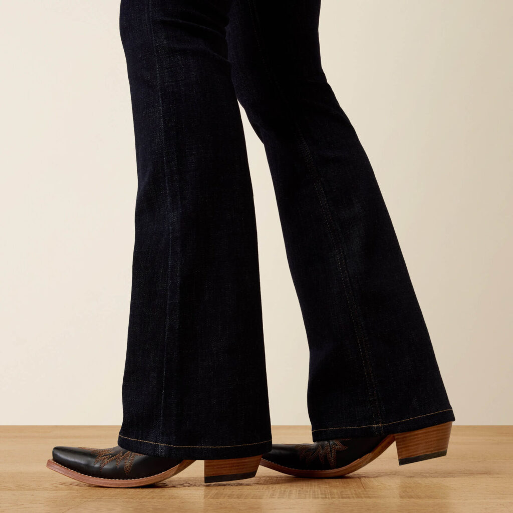Dark rinse jeans stacked over black pointed-toe cowboy boots, close-up