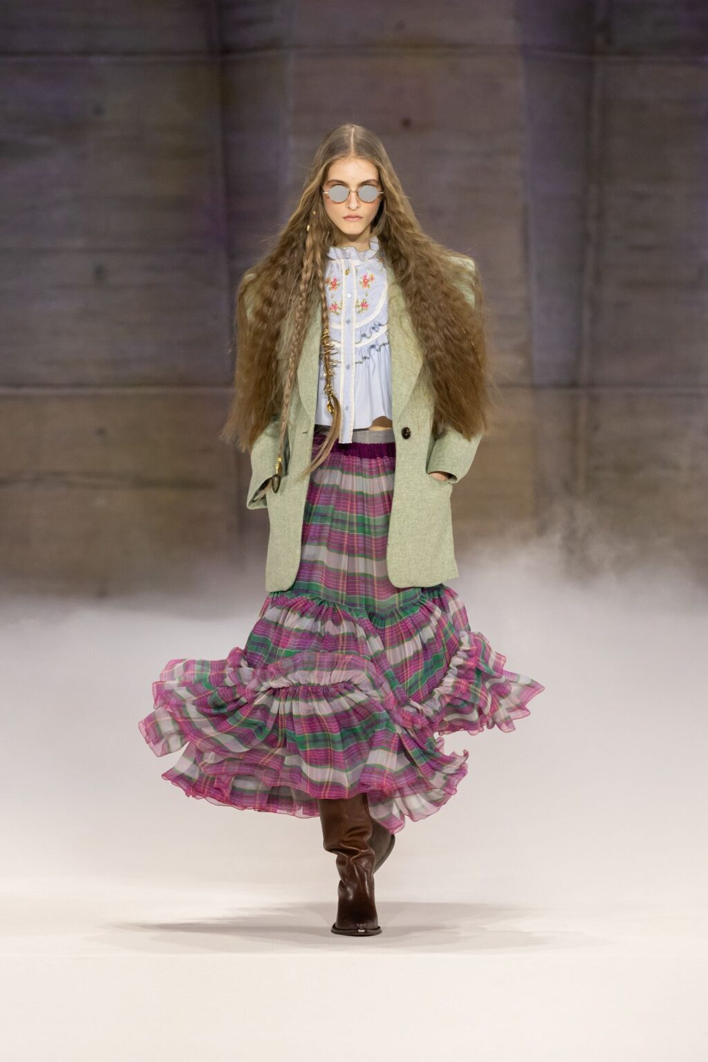 Chloé Fall 2026 look 1: sage green jacket, embroidered blouse and tiered pink-and-green plaid skirt with brown boots