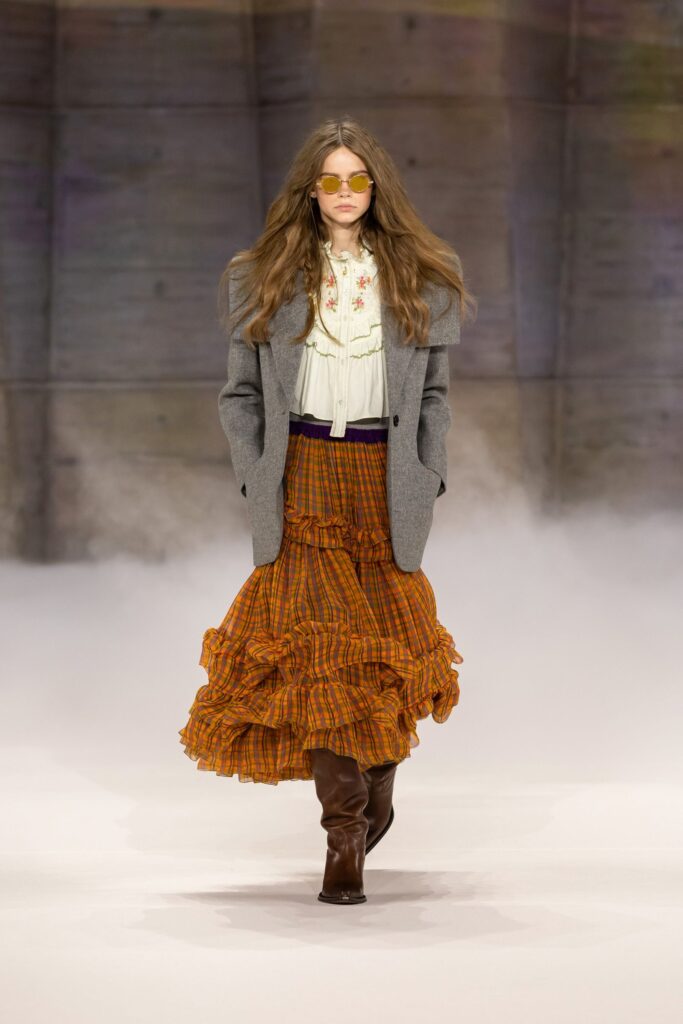 Chloé Fall 2026 look 2: gray blazer, ruffled blouse and tiered orange check skirt with brown boots