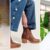Cowboy booties outfit ideas: Chloé Fall 2026 look 4 with a sheer tiered skirt and brown boots, a close-up of jeans over a brown Tecovas short-shaft bootie, and Louis Vuitton Fall 2026 look 31 with a short plaid skirt and short boots