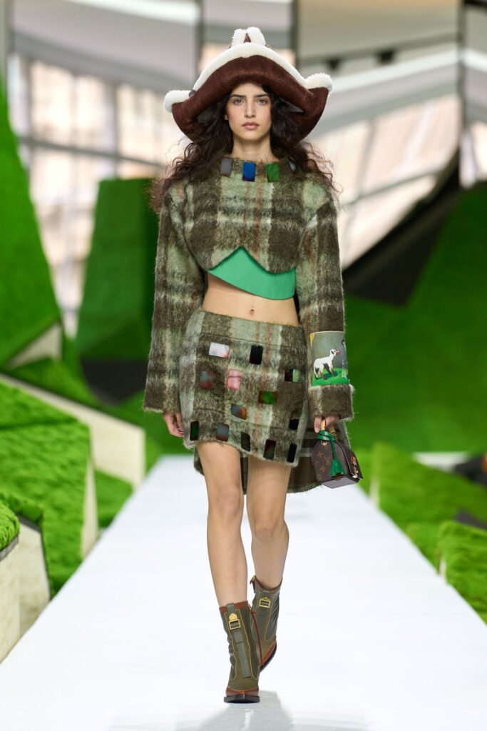 Louis Vuitton Fall 2026 look 31: a cropped plaid jacket and short plaid skirt with a wide-brim hat and short boots