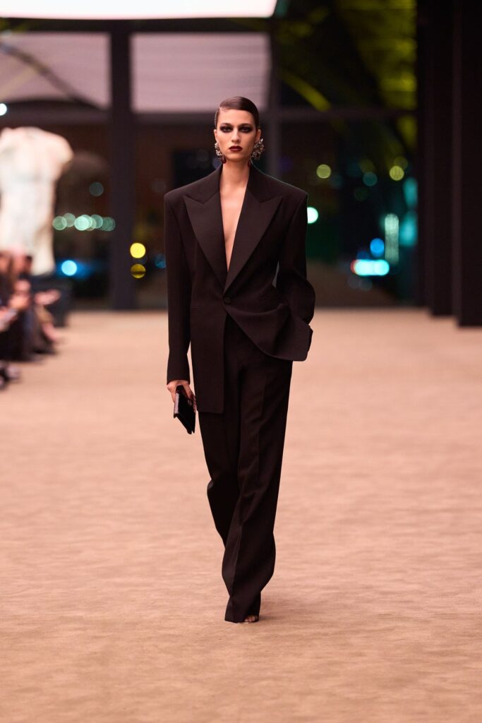 Saint Laurent Fall 2026 look 49: black single-breasted tuxedo jacket worn with nothing underneath and wide black trousers