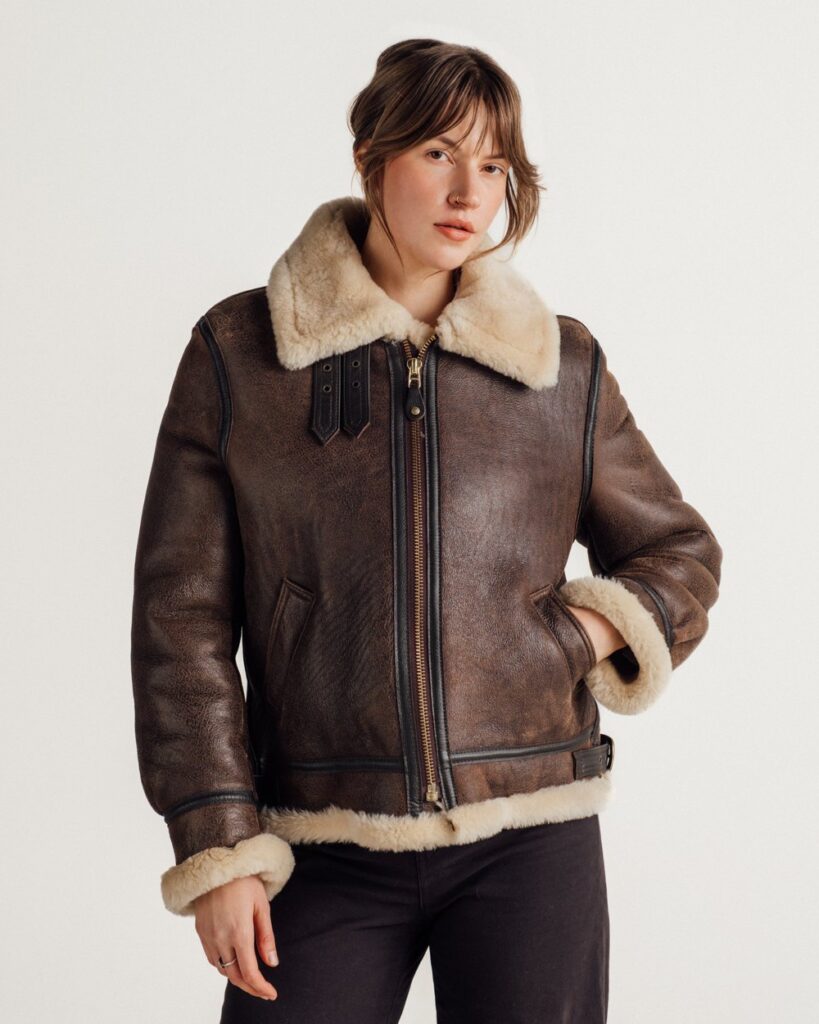Schott 247SW women's brown sheepskin B-3 bomber jacket with a cream shearling collar and cuffs, worn with dark trousers