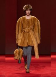 Shearling coat outfit ideas from Bottega Veneta Fall 2026: a shaggy cream jacket with a red collar over black trousers, a belted camel shaggy coat with grey tights, and a long cream shaggy coat with a camel belt (looks 43, 49 and 40)