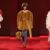 Shearling coat outfit ideas from Bottega Veneta Fall 2026: a shaggy cream jacket with a red collar over black trousers, a belted camel shaggy coat with grey tights, and a long cream shaggy coat with a camel belt (looks 43, 49 and 40)