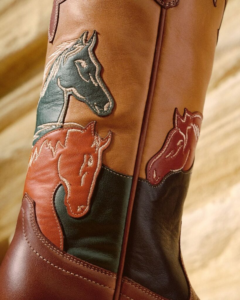 Close-up of the Tecovas Annie Wild Horses boot shaft with stitched horse-head overlays in teal, rust and tan leather