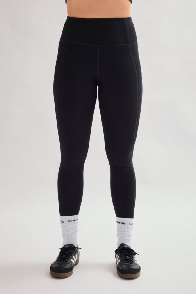 Girlfriend Collective Compressive High-Rise Legging in black, worn with white socks and black sneakers